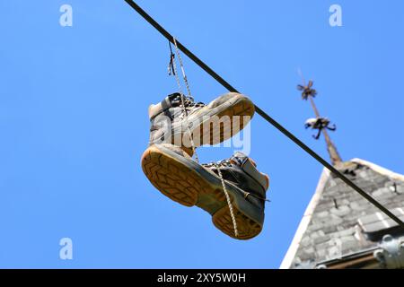 Schuhe, die in großer Höhe an einer Freileitung hängen Stockfoto