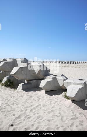 Wellen, die Betonblöcke am Strand ableiten. Stockfoto