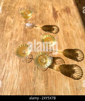 Vintage-Gläser gefüllt mit Champagner in direktem Sonnenlicht Stockfoto