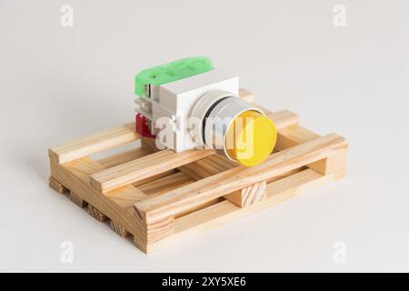 Eine Industrietaste für industrielle Schalttafeln von gelben Geräten liegt auf einer Holzpalette. Start-Stopp-Taste Stockfoto