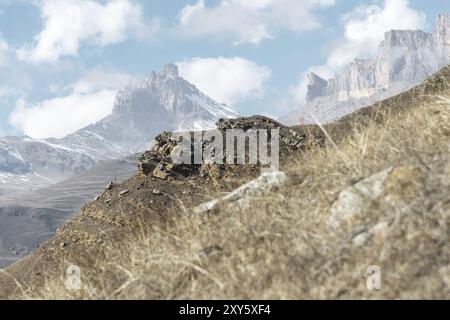 Herbstliche Berglandschaft mit gelblichen Hängen und Gras in den Bergen mit epischen Felsen und Teilen von schneebedeckten Hängen an einem sonnigen Tag gegen den bl Stockfoto