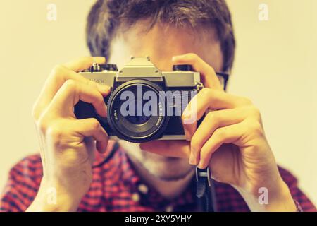 Junger Mann in rot-blau kariertes Hemd ist ein Bild mit einem Vintage Kamera, retro style Stockfoto