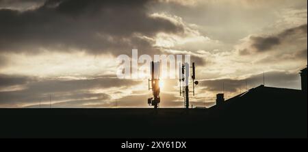 Silhouette von Kommunikation oder Zellturm auf dem Dach eines Gebäudes, Abendsonne Stockfoto