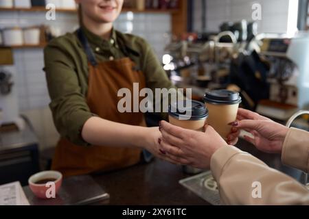 Frau Barista serviert Kaffee in Tassen zum Mitnehmen Stockfoto