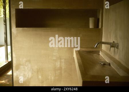 Badezimmer mit industriellem Design aus Beton mit Betonwaschbecken, wandmontiertem Wasserhahn und eingelassenen Regalnischen Stockfoto
