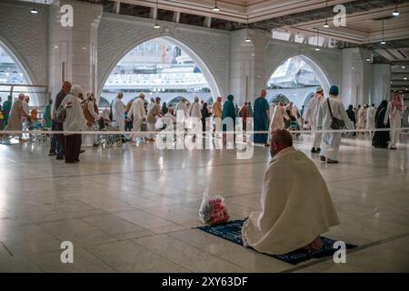 Unbekannte muslimische Pilger beobachten, wie andere Pilger Tawaf (Umgehungen) von Kaaba im zweiten Stock der Masjid-Haram-Moschee in Mekka durchführen. Stockfoto