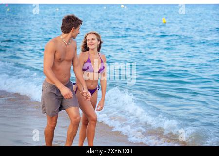 Glückliches junges Paar, das am Strand zusammen läuft Stockfoto