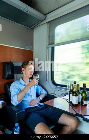 Junger Mann, der im Abteil des fahrenden Zuges sitzt Stockfoto