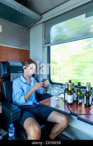 Junger Mann, der im Abteil des fahrenden Zuges sitzt Stockfoto