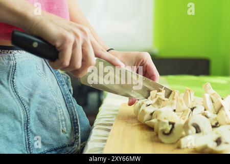 Kochen Von Pilzen. Schneiden. Weibliche Hände auf einem Schneidebrett in große Holzpilze geschnitten. Das Konzept des Kochens zu Hause. Das Konzept der Heilung Stockfoto