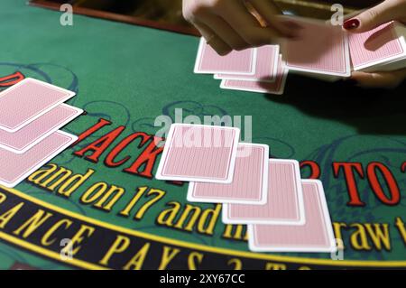 Hände eines Croupier-Händlers an einem Blackjack-Kartentisch, der die Karten in einem Casino ausgibt Stockfoto