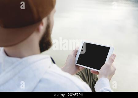 Hipster Person hält in Händen digitales Tablet mit leerem Bildschirm, Mann Foto auf Computer auf Hintergrund Natur Outdoor Landschaft Mock up Tech Stockfoto