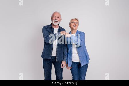 Porträt eines glücklichen Seniorenpaares, das lacht und Faustschläge gibt, während es auf weißem Hintergrund steht Stockfoto