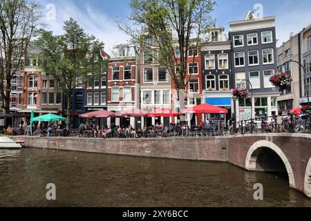 AMSTERDAM, NIEDERLANDE - 10. JULI 2017: Besucher besuchen den Oudezijs Voorburgwal Kanal in Amsterdam, Niederlande. Der Canal Ring aus dem 17. Jahrhundert liegt in der Nähe der Stadt Stockfoto