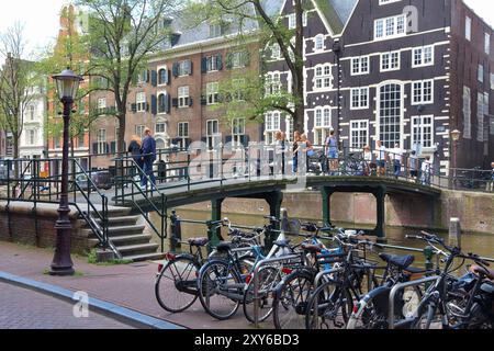 AMSTERDAM, NIEDERLANDE - 10. JULI 2017: Besucher besuchen den Oudezijs Achterburgwal Kanal in Amsterdam, Niederlande. Das Gebiet des Kanalrings aus dem 17. Jahrhundert Stockfoto
