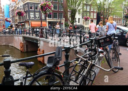 AMSTERDAM, NIEDERLANDE - 8. JULI 2017: Menschen überqueren den Kloveniersburgwal-Kanal in Amsterdam, Niederlande. Amsterdam ist die Hauptstadt der Niederlande Stockfoto
