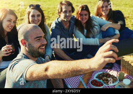 Freunde, Selfie und glücklich in der Natur für Picknick, Wiedersehen oder Mittagessen im Freien im Urlaub. Gruppen, Essen oder Lächeln auf Gras zum Fotografieren, Binden oder Machen Stockfoto