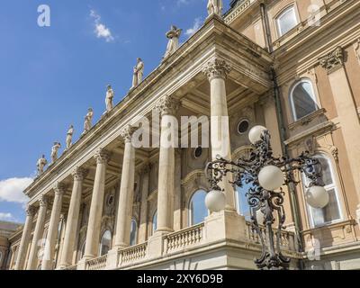 Eine imposante Fassade mit mehreren Säulen und einer kunstvollen Straßenlaterne vor einem blauen Himmel, budapest, donau, ungarn Stockfoto
