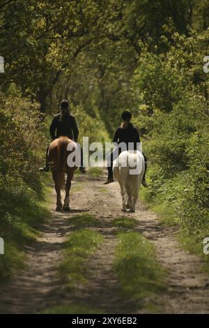 Zwei Mädchen zu Pferd auf einer idyllischen Landstraße Stockfoto