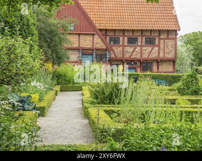 Gepflegter Garten mit einem Fachwerkhaus im Hintergrund, wo ein Weg durch gepflegte grüne Hecken führt, ystad, schweden, ostsee, Skandinav Stockfoto