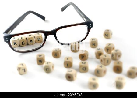 Brille und Lesebrille in Holzblöcken geschrieben, isoliert auf weißem Hintergrund, einige unscharfe Buchstaben herum, Symbol, Konzept Stockfoto