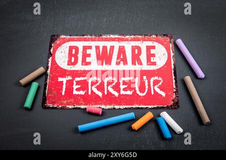 Terror, Wort auf Französisch. Achtung: Schild mit Text und farbigen Kreideflächen auf dunklem Tafel-Hintergrund. Stockfoto