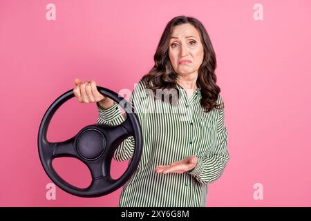 Porträt der hübschen alten Dame Show halten Rad tragen gestreiftes Hemd isoliert auf rosa Hintergrund Stockfoto