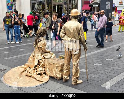 Straßenkünstlerpaar, lebende Statue, gekleidet in goldenem Outfit am Leicester Square, London, Großbritannien Stockfoto