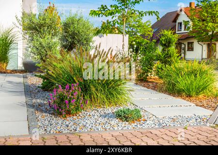 Der Innenhof eines modernen Hauses, Gartendetails mit bunten Pflanzen, trockene Grasbetten umgeben von grauen Felsen. Stockfoto