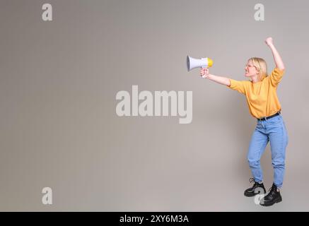 Junge Aktivistin mit handerhobenem Megaphon und Protest vor weißem Hintergrund Stockfoto
