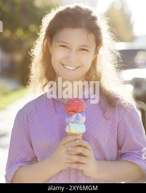 Kleines lächelndes Mädchen, das draußen Eisbecher in den Händen hält Stockfoto