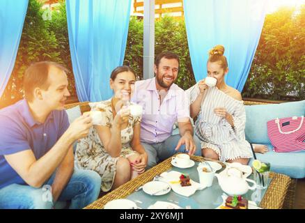 Freudige Freunde sitzen, Tisch im Cafe im Freien serviert. Stockfoto