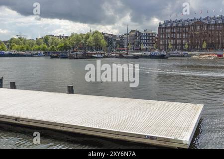 Ein ruhiger Hafen mit einem Holzsteg und historischen Gebäuden im Hintergrund, Amsterdam, Niederlande Stockfoto