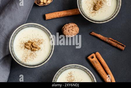 Pudding in Glasschale mit Zimt und Walnuss auf rustikalem Tisch, Milchdessert Stockfoto