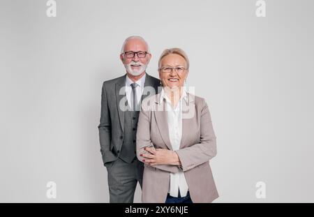 Selbstbewusster reifer Geschäftsmann und Geschäftsfrau in Brille lächelnd und stehend auf weißem Hintergrund Stockfoto
