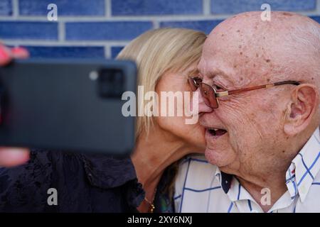 Älterer Vater und Tochter küssen und lächeln für die mobile Kamera Stockfoto