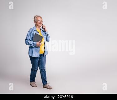 Lächelnde Geschäftsfrau mit Tablet, die über Mobiltelefon diskutiert und auf weißem Hintergrund wegblickt Stockfoto
