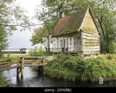 Kleine Holzhütte mit moosbedecktem Dach und Holzbrücke über einen kleinen Bach, eingebettet in die Natur, Bad Zwischenahn, ammerland Stockfoto