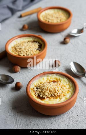 Gebackener Reispudding türkisches Milchdessert Sutlac in Auflauf mit Zimtstangen und gehackten Haselnüssen Stockfoto