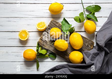 Frische reife gelbe Zitronenfrüchte mit Blättern auf rustikalem Hintergrund Stockfoto
