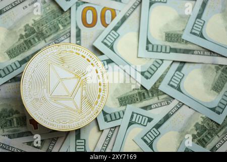 KIEW, UKRAINE - 17. AUGUST 2024 Ethereum-ETH-Münze auf große Menge von hundert US-Dollar-Scheinen nahe oben Stockfoto