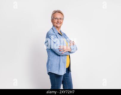 Hochrangige Profi mit überkreuzten Armen lächelnd und selbstbewusst auf weißem Hintergrund stehend Stockfoto