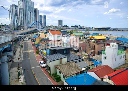 Sokcho City, Südkorea - 28. Juli 2024: Aus der Vogelperspektive auf die bunten Dächer des Abai Village mit der riesigen Geumgang Grand Bridge im Backgr Stockfoto