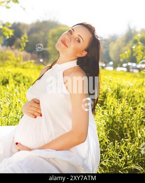 Porträt von schöne schwangere Frau in weißem Kleid im Frühjahr blühenden park Stockfoto