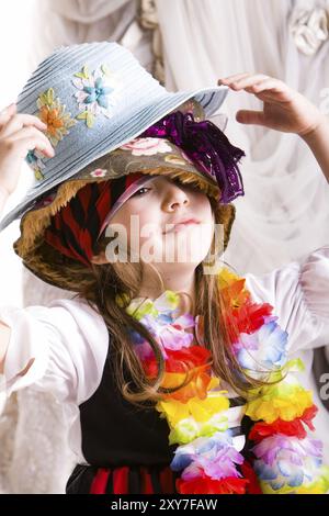 Kleines Mädchen, das sich mit einem Haufen Hüte verkleidet Stockfoto