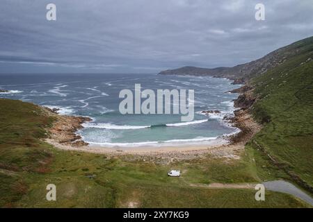 Drohnenansicht eines Wohnwagens an einem wilden Strand mit grüner Landschaft in Galicien, Spanien, Europa Stockfoto