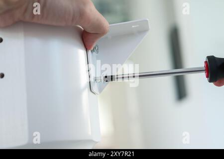 Asiatischer Mann, der weiße Tischmöbel zu Hause zusammenbaut Stockfoto