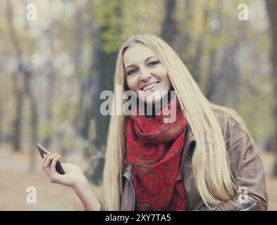 Porträt einer lächelnden schönen Frau SMS SMS im Herbst park Stockfoto