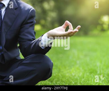 Geschäftsmann entspannend in einem Park im Lotussitz. Nahaufnahme Stockfoto
