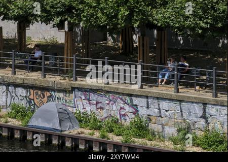 Deutschland, Berlin, 09.07.2024, Hitze im Sommer in Berlin, Spreeufer, Zelt eines Obdachlosen, Bürger auf Bänken, Europa Stockfoto